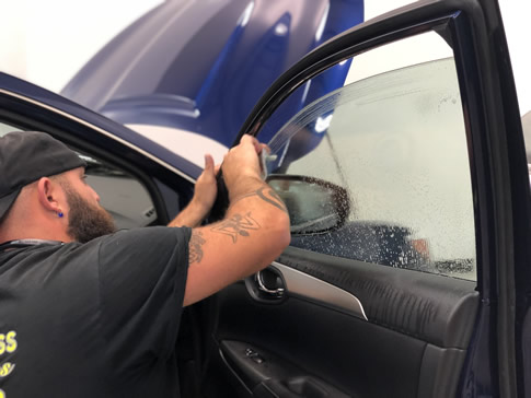 Technicial installing window tint on car door window
